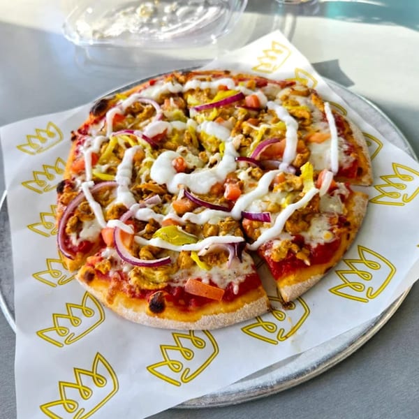 A Build-A-Pita & Pizza restaurant pizza with chicken, red onions, peppers, and white sauce.