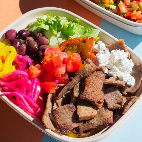 A Build-A-Pita bowl filled with gyro meat, lettuce, olives, tomatoes, pickled onions, and feta cheese.