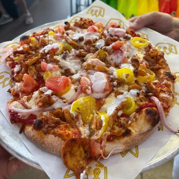 A Build-A-Pita & Pizza Restaurant pizza with chicken, tomatoes, peppers, and white sauce.